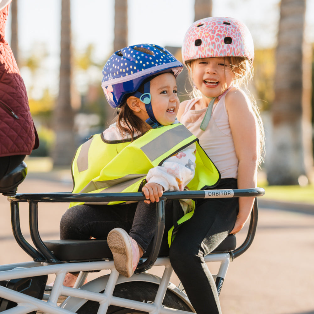 Des enfants portant des casques de vélo roulent dans l'Orbitor, assis sur des coussins à l'arrière du Lectric XPedition