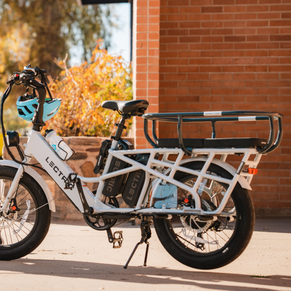 Lectric XPedition double batterie stationnée avec coussins et orbiteur et casque de vélo bleu sur guidon