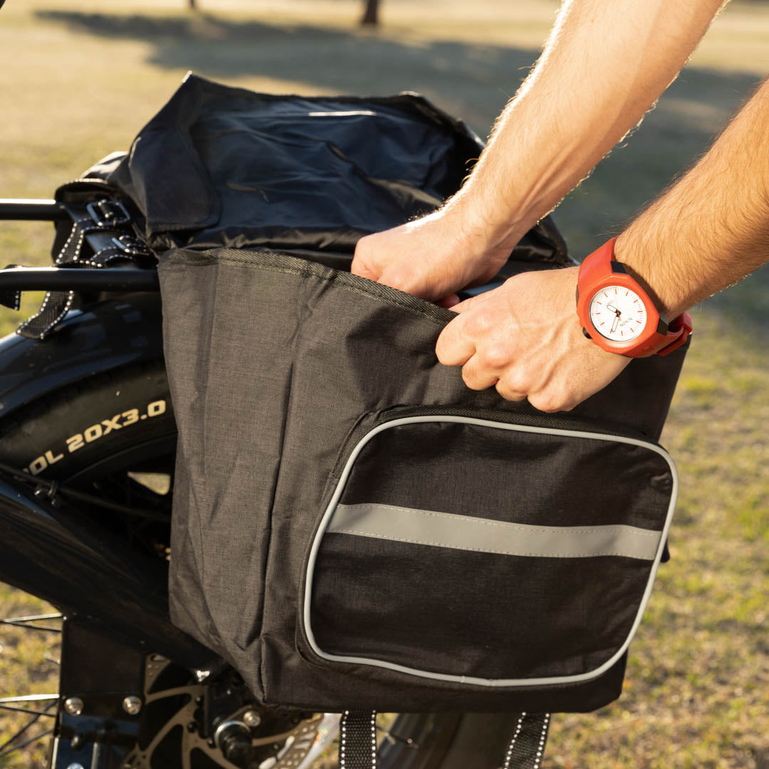 On voit des mains qui plongent dans un sac de sacoche à l’arrière d’un vélo