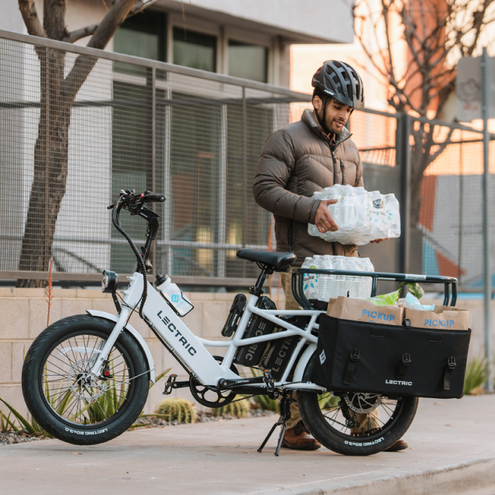 Homme chargeant des caisses d’eau dans l’orbiteur et des courses dans des sacoches XL Cargo sur Lectric XPedition
